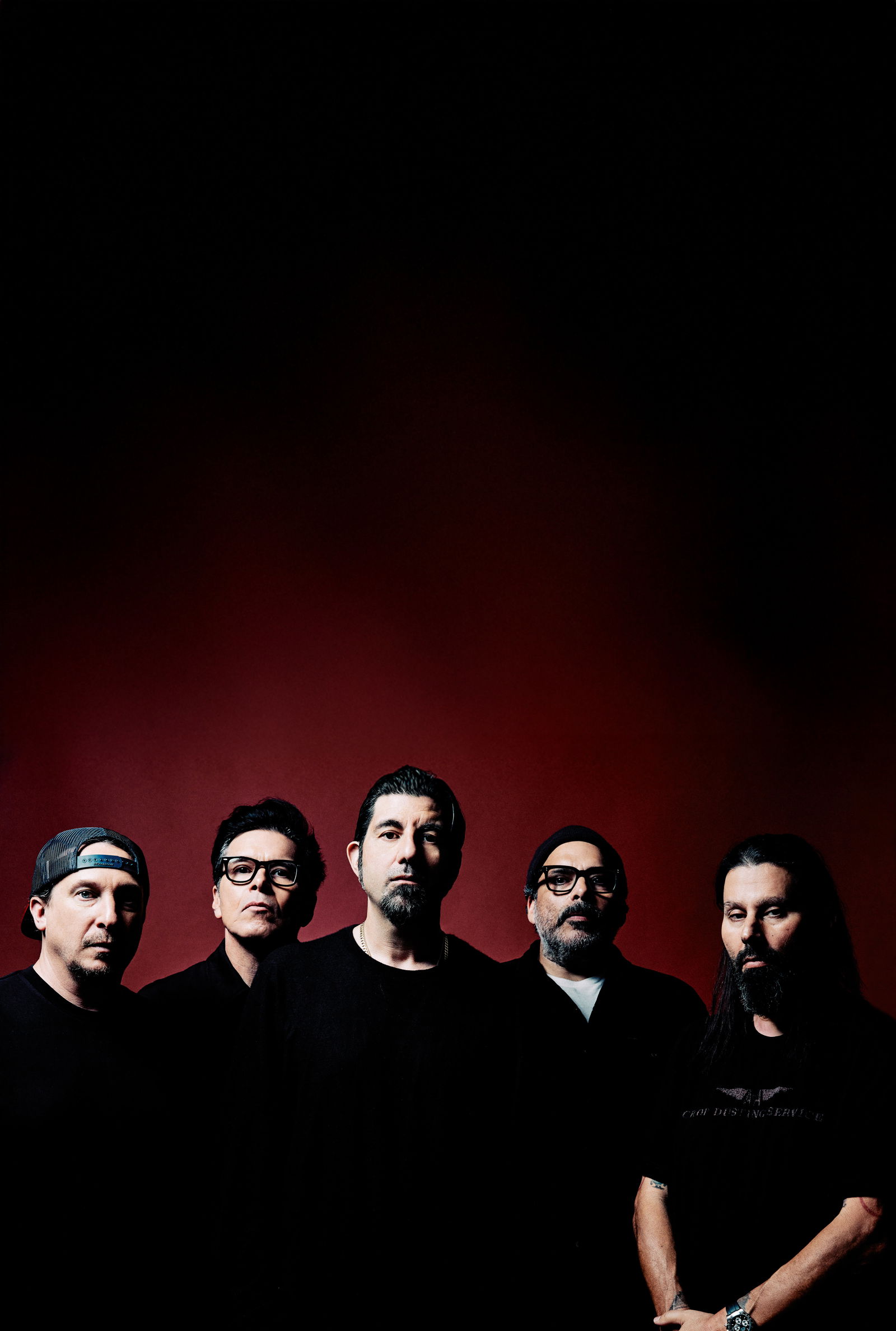 Deftones Pressefote, die Bandmitglieder stehen vor einem einfarbigen, roten Hintergrund